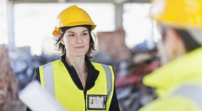 En kvinne iført arbeidstøy som snakker med en kollega