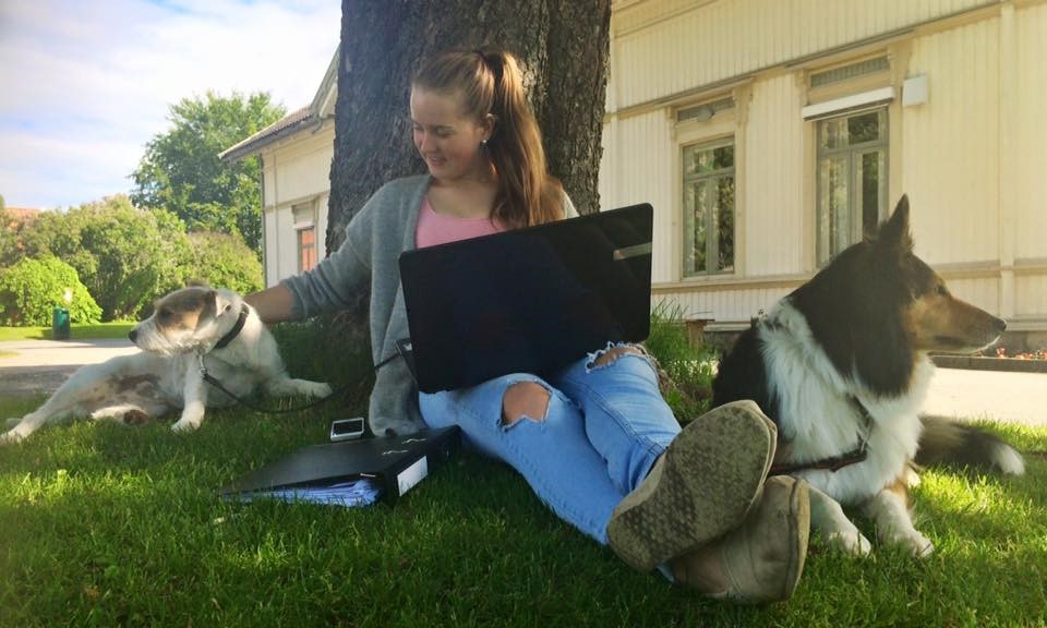 Skoleelev som sitter på gresset sammen med to hunder