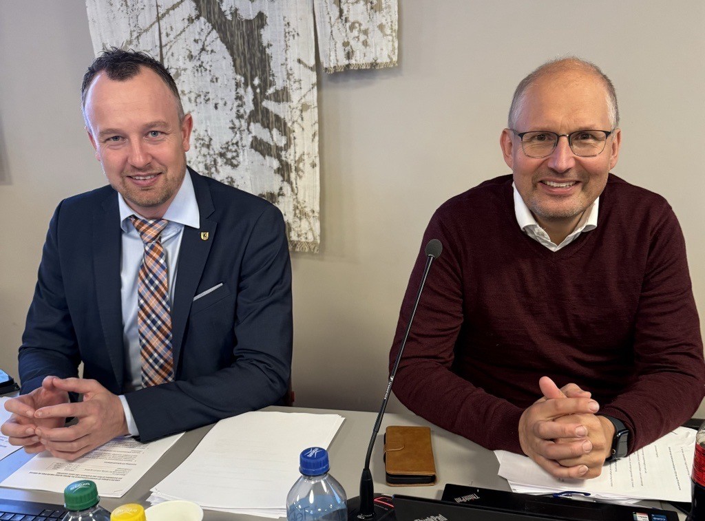 To menn som ser i kamera og smiler