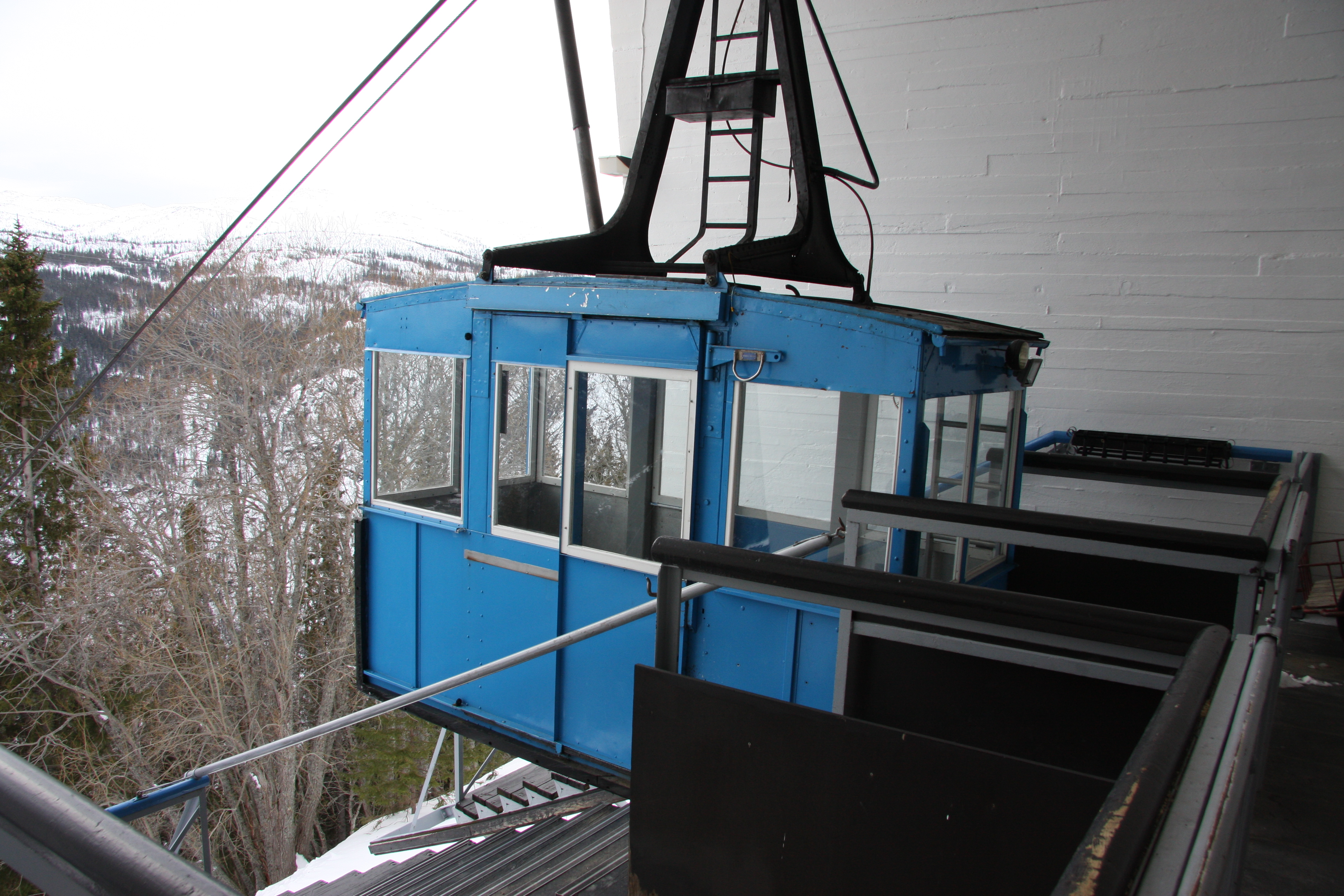 Bilde tatt fra toppen av gondolbanen og viser en blå passasjervogn.