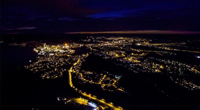 Oversiktbilde av en by om natten med masse lys.