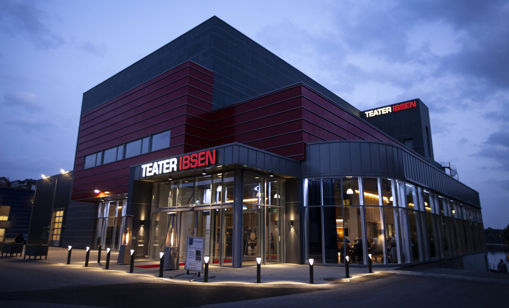 Bilde av et bygg i skumringen, hvor lysene er på.