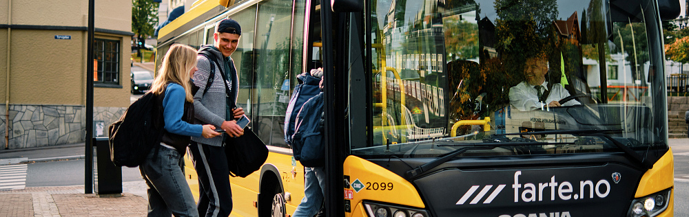 Tre ungdommer på vei inn i buss fra venstre. Bussen plassert midt i bildet. Sjåføren skimtes gjennom frontrute på buss.