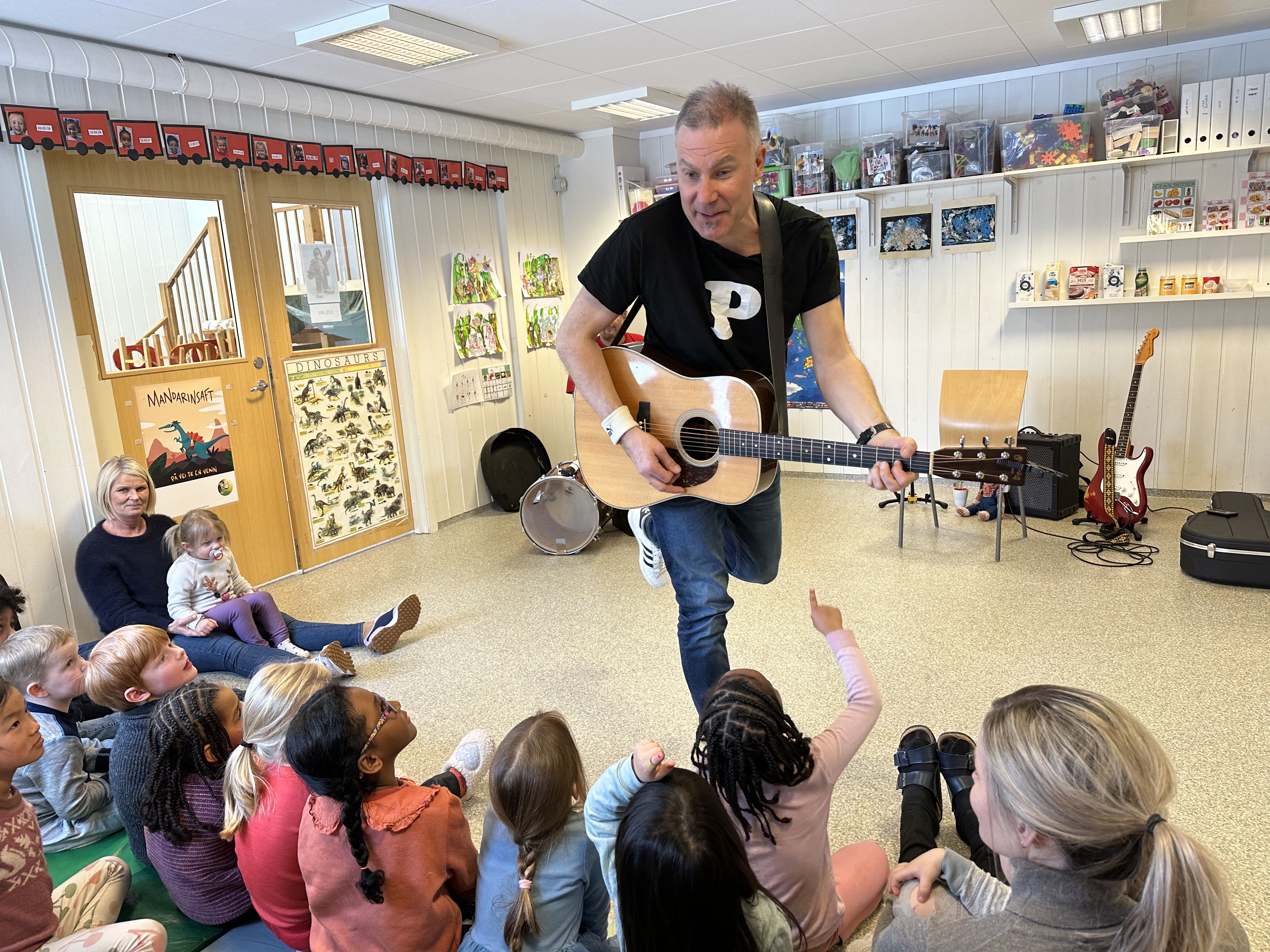 Mann med gitar spiller for barn