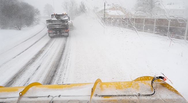 Brøytebil som kjører etter en annen lastebil på veier med mye snø.