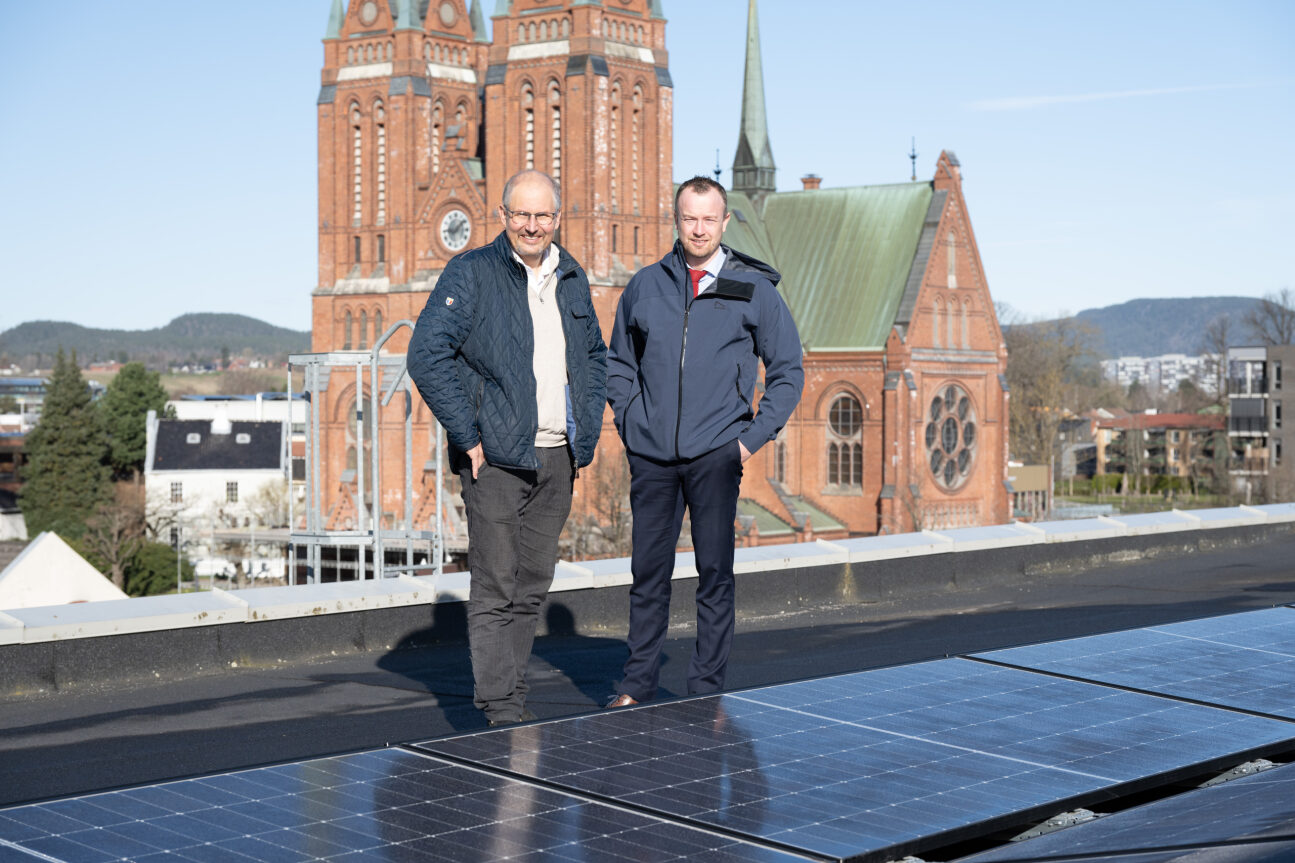 To menn på taket av Telemarkshuset. Skien kirke er synlig i bakgrunn.